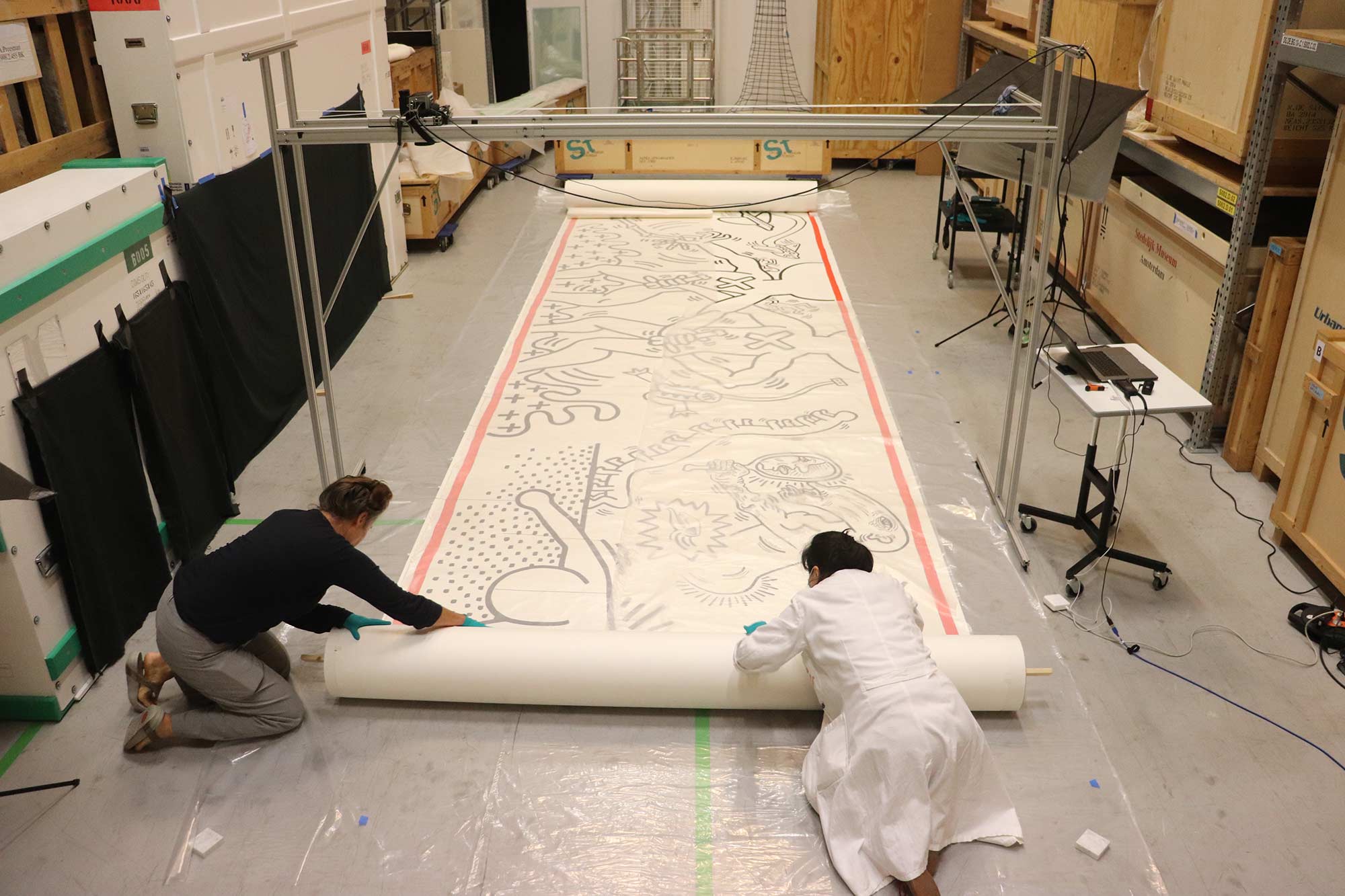 Unrolling the work for the condition report, 2022. Photo: Femke Segers. Amsterdam Notes © Keith Haring Foundation.