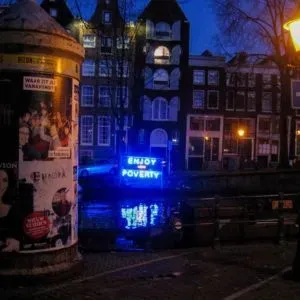 Figure 2. Renzo Martens, Enjoy Poverty, remade neon sign from Episode 3 roaming an Amsterdam canal around the premiere of the film, November 2008. Photo: Jelle Bouwhuis.